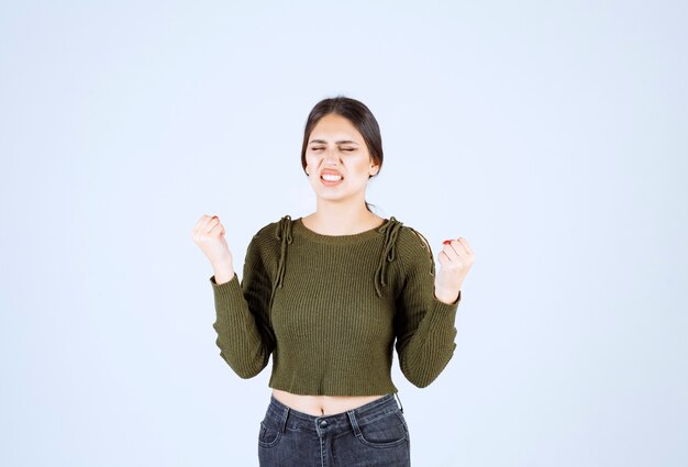 Porträt eines jungen schönen Frauenmodells, das über weißer Wand steht und aufwirft.