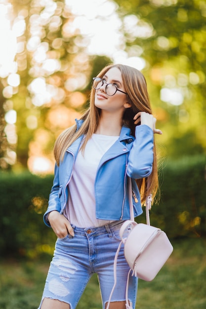 Porträt eines jungen schönen Mädchens in Gläsern in Jeans mit stylischen Hosen