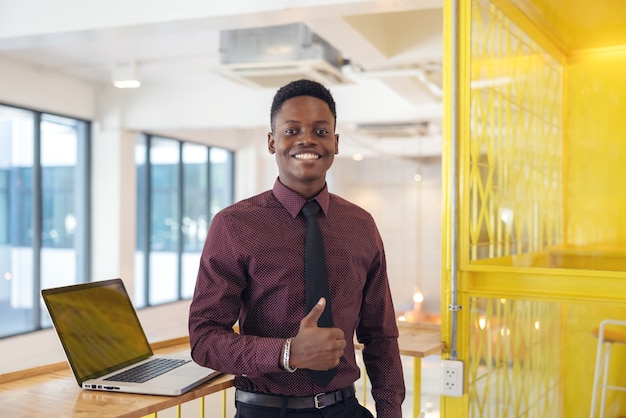 Porträt eines jungen schwarzen mannes, der einen laptop in einer arbeitsumgebung verwendet, entweder ein afrikanischer geschäftsmann oder ein student.