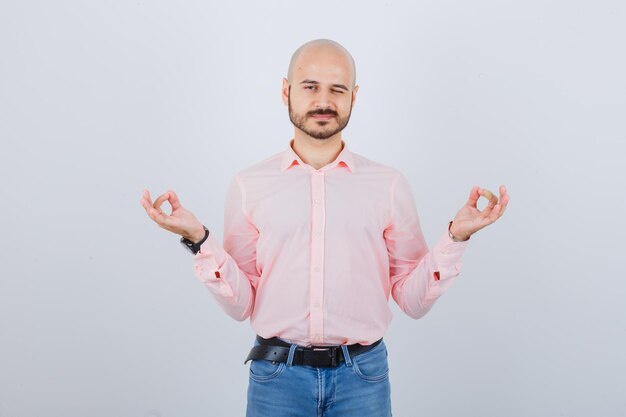 Porträt eines jungen selbstbewussten Mannes, der Meditationsgeste zeigt