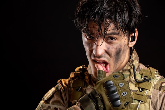 Porträt eines jungen Soldaten in Uniform an einer dunklen Wand