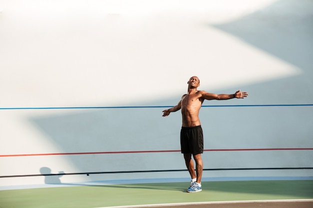 Porträt eines jungen Sportlers in voller Länge, der Dehnübungen macht