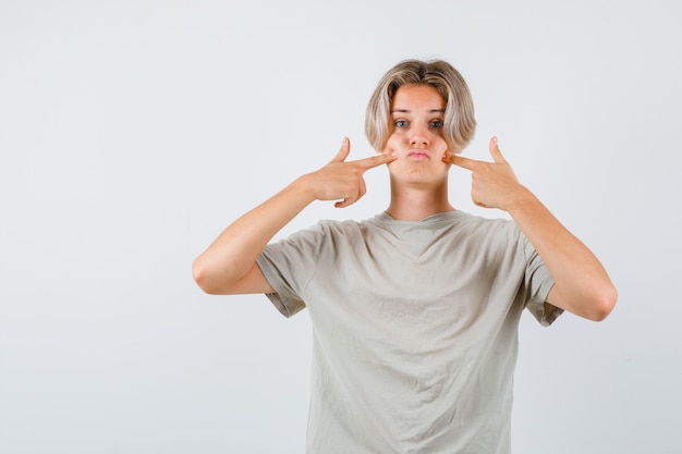 Porträt eines jungen Teenagers, der die Finger auf die geschwollenen Wangen im T-Shirt drückt und verwirrte Vorderansicht schaut