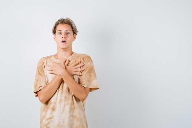 Porträt eines jungen Teenagers, der im T-Shirt gekreuzte Hände auf der Brust hält und verängstigte Vorderansicht schaut