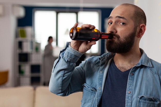 Porträt eines kaukasischen Mannes mit einer Flasche Bier bei einem Treffen mit Kollegen nach der Arbeit. Person, die Spaß mit Freunden im Geschäftsbüro hat und Partyfeiern mit Essen und Alkohol genießt.