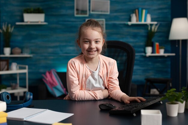 Porträt eines kleinen Grundschulkindes, das zu Hause am Schreibtisch sitzt