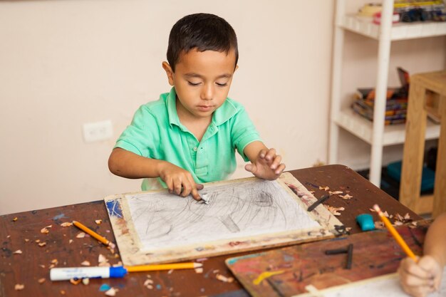 Porträt eines kleinen Jungen, der an einer Zeichnung für seinen Kunstunterricht in der Schule arbeitet