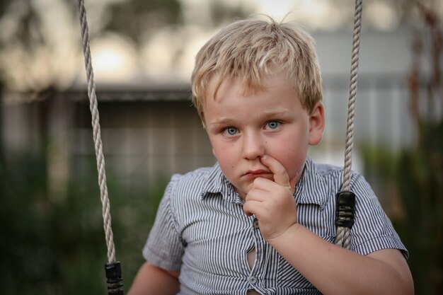 Porträt eines kleinen Jungen, der in einem hübschen Garten sitzt