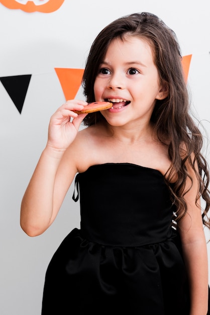 Porträt eines kleinen Mädchens, das ein Plätzchen isst