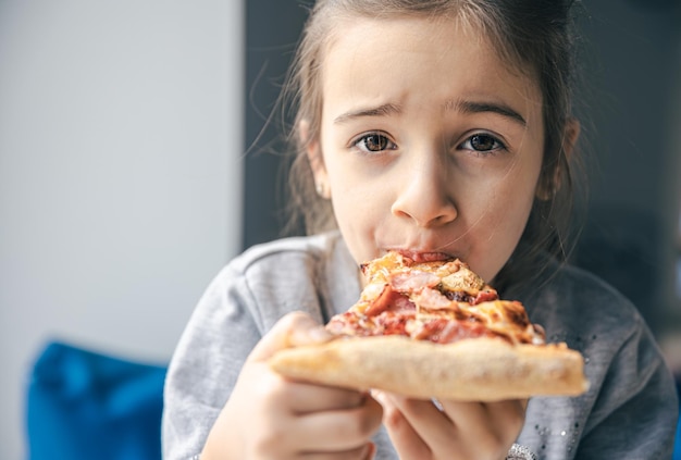 Porträt eines kleinen Mädchens mit einem appetitlichen Stück Pizza