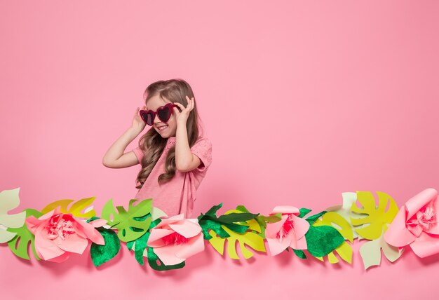 Porträt eines kleinen Mädchens mit Sonnenbrille auf einem rosa Hintergrund