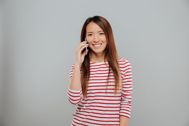Porträt eines lächelnden asiatischen Mädchens, das auf Handy spricht