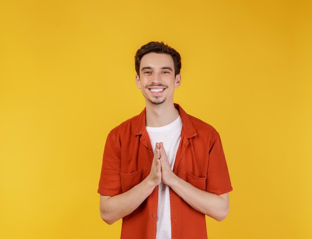 Porträt eines lächelnden gutaussehenden Mannes in Pay-Respekt-Pose, der über gelbem Hintergrund steht