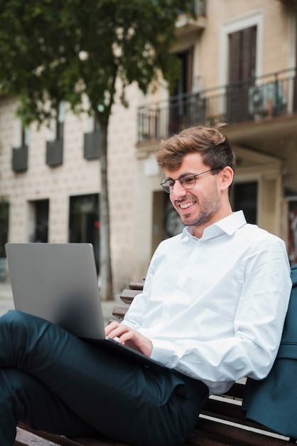 Porträt eines lächelnden jungen Geschäftsmannes unter Verwendung des Laptops