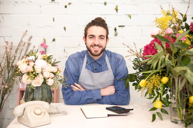 Kostenloses Foto porträt eines lächelnden jungen männlichen floristen mit den bunten blumen im shop