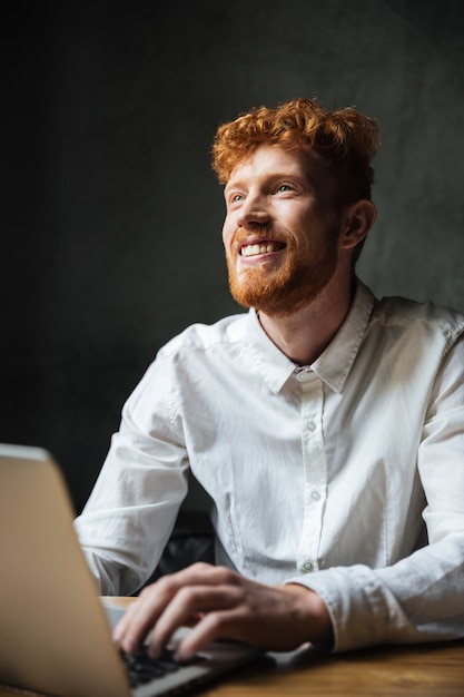 Kostenloses Foto porträt eines lächelnden jungen mannes, der auf einem laptop tippt