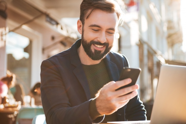 Porträt eines lächelnden jungen Mannes, der Handy hält