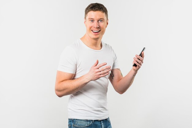 Porträt eines lächelnden jungen Mannes, der in der Hand den Handy schaut zur Kamera hält