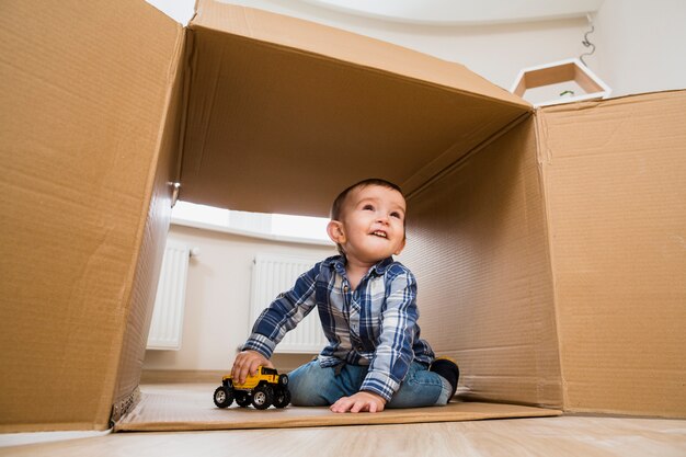 Porträt eines lächelnden Kleinkindjungen, der mit Spielzeugfahrzeugen spielt