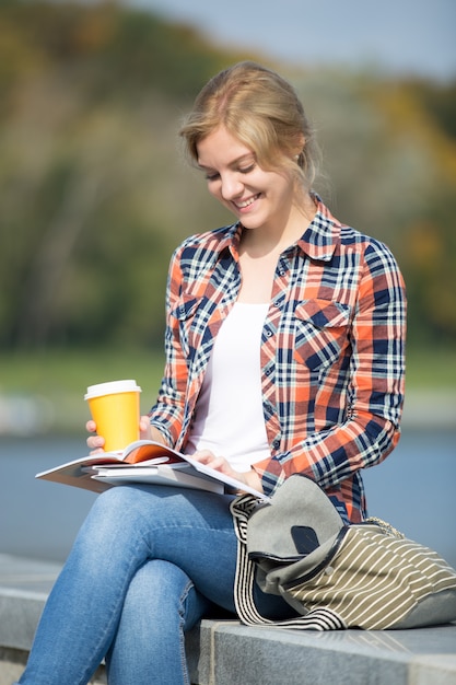 Porträt eines lächelnden Mädchens sitzen an der Brücke lesen