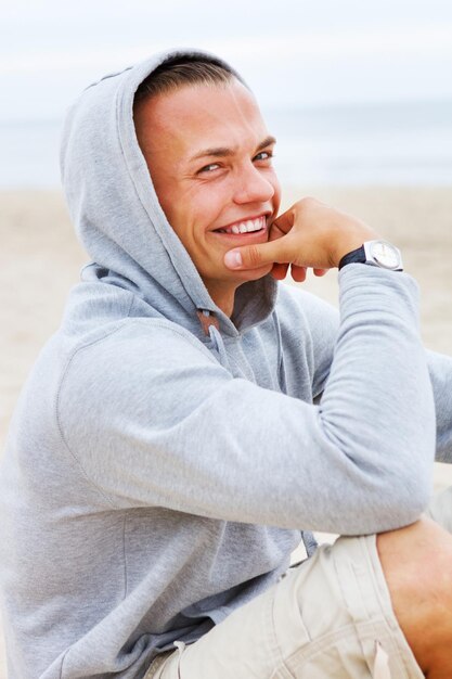 Porträt eines lächelnden Mannes, der am Strand sitzt