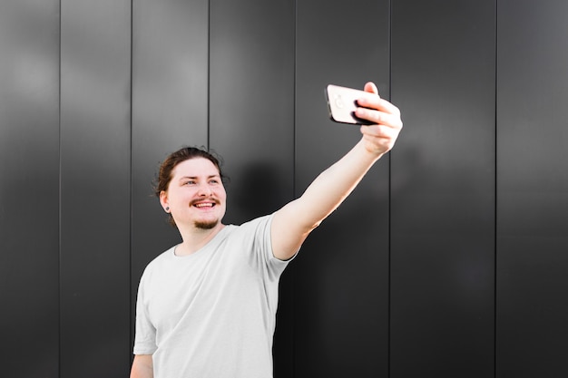 Porträt eines lächelnden Mannes, der selfie am Handy nimmt