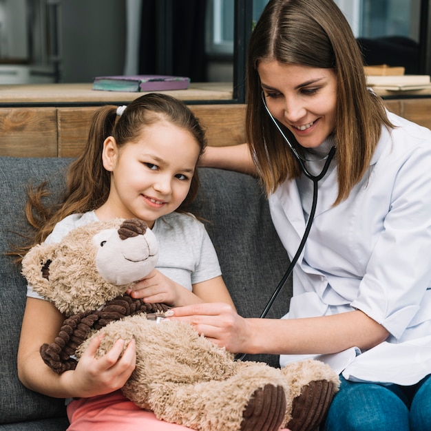 Porträt eines Mädchens, das den Teddybären mit Stethoskop überprüft