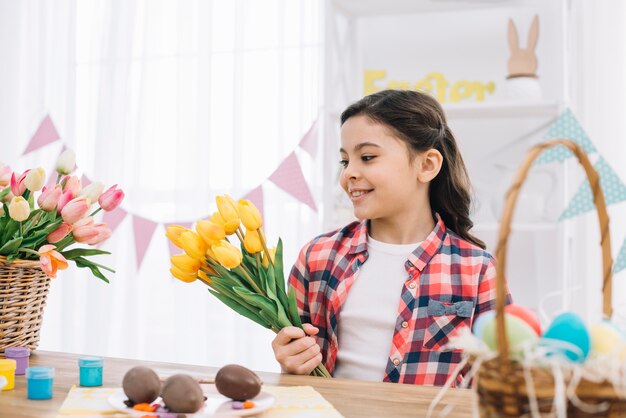 Porträt eines Mädchens, das gelbe Tulpe betrachtet, blüht an Ostern-Tag