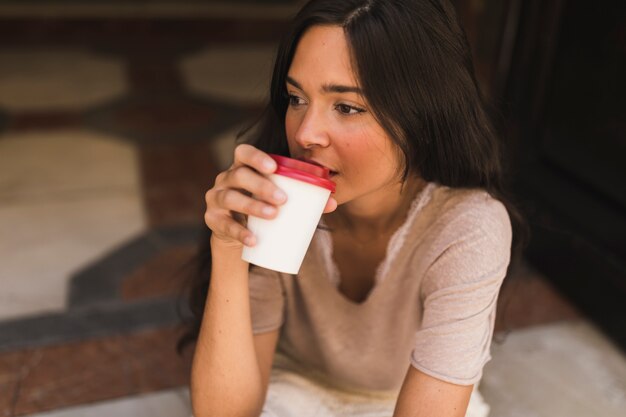 Porträt eines Mädchens, das Kaffee von der Wegwerfschale trinkt