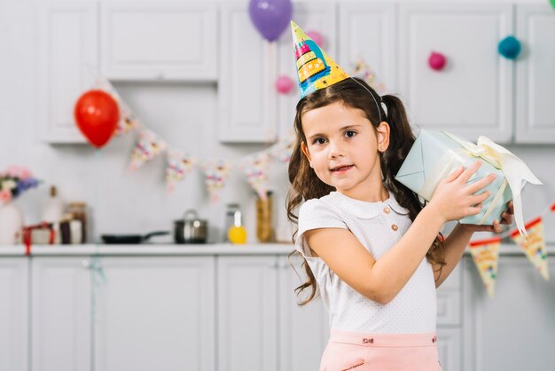 Porträt eines Mädchens mit dem Geburtstagsgeschenk, das Kamera betrachtet