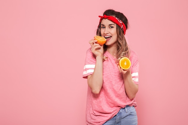 Porträt eines Mädchens mit Orangen in der Hand, auf einem rosa Hintergrund