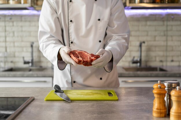 Porträt eines männlichen Kochs in der Küche, der Fleisch zubereitet