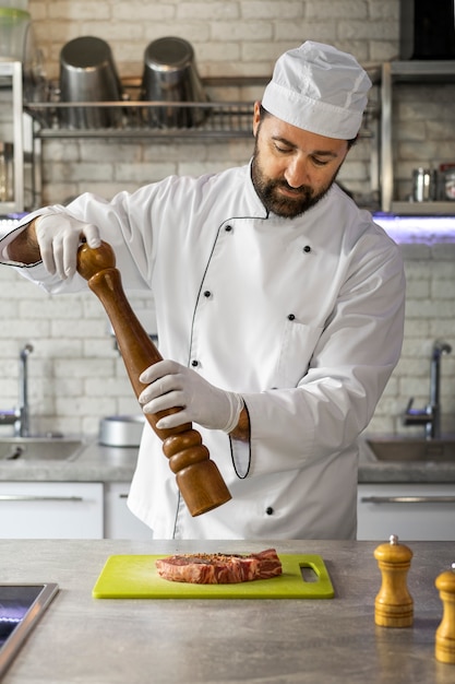 Porträt eines männlichen Kochs in der Küche, der Fleisch zubereitet