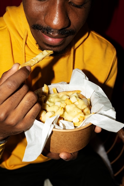 Kostenloses Foto porträt eines mannes, der ein köstliches gericht aus poutine isst