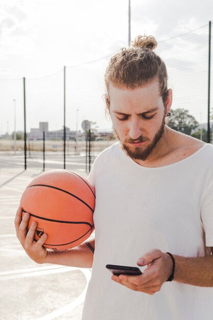 Porträt eines Mannes mit Basketball unter Verwendung des Handys