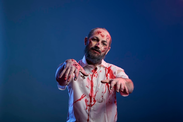 Porträt eines menschlichen zombies mit kratzern und finsteren wunden, die vor der kamera posieren, gefährliche untote leiche mit gruseligen narben und gruseligem gesicht im studio. doomsday grausamer monsterteufel.