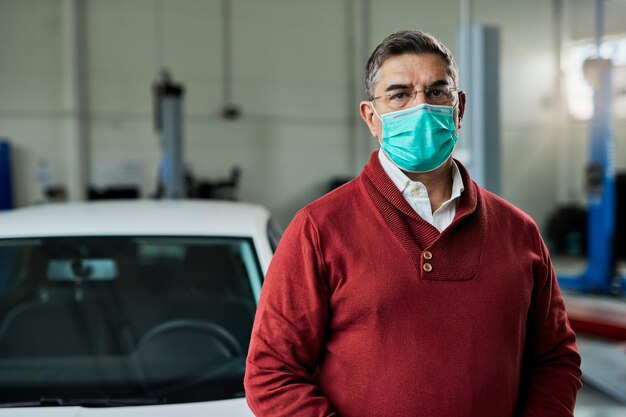 Porträt eines mittleren erwachsenen Mannes mit schützender Gesichtsmaske in der Autowerkstatt