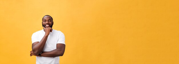 Porträt eines modernen jungen schwarzen Mannes, der mit den Armen lächelt, kreuzte auf lokalisiertem gelbem Hintergrund