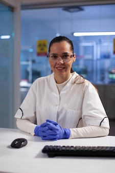 Porträt eines praktizierenden forschers in medizinischer uniform, der an der impfstoffentwicklung gegen coronavirus arbeitet. chemiker, der die testergebnisse der patientenkrankheit während des mikrobiologischen experiments analysiert