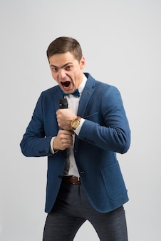 Porträt eines professionellen männlichen reporters, der ein mikrofon hält, isoliert auf weißem und grünem hintergrund