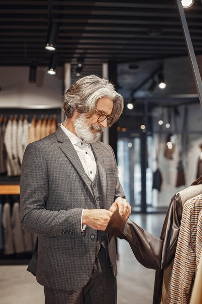 Porträt eines reichen reifer Mannes. Senior besucht eine Modeboutique. Männer kaufen ein neues exklusives Kostüm.