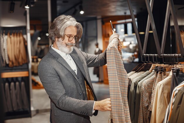 Porträt eines reichen reifer Mannes. Senior besucht eine Modeboutique. Männer kaufen ein neues exklusives Kostüm.