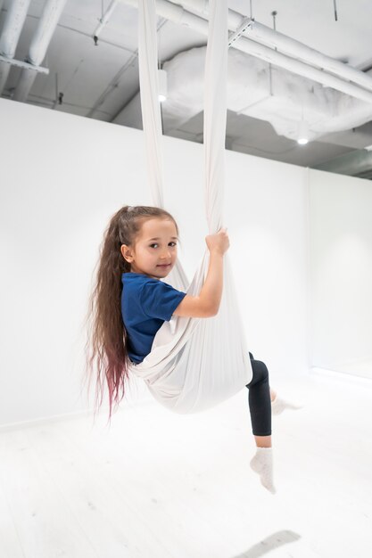 Porträt eines schönen jungen Mädchens beschäftigt sich mit Fliegenyoga auf Leinwänden.