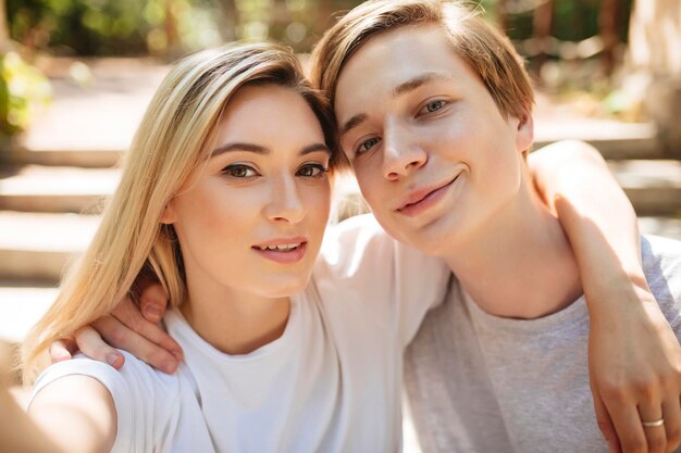 Porträt eines schönen jungen Paares, das zusammen ein Selfie macht Cooler Junge und hübsches Mädchen mit blonden Haaren, die glücklich in die Kamera schauen, während sie Fotos mit der Frontalkamera des Mobiltelefons machen