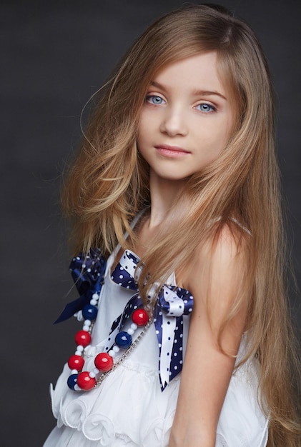 Porträt eines schönen kleinen Mädchens mit blonden Haaren auf grauem Hintergrund