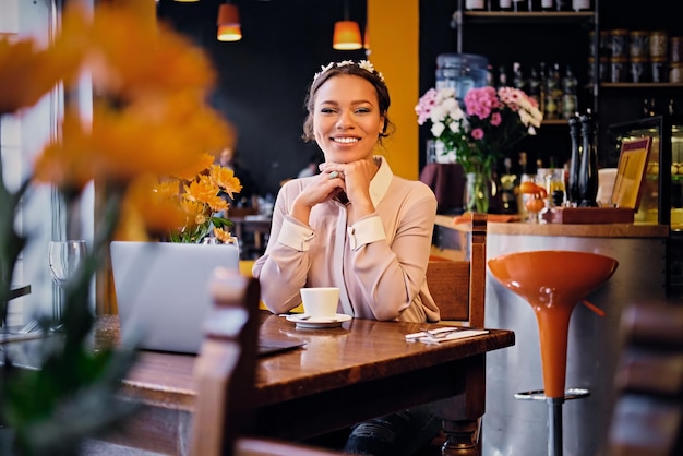 Porträt eines schwarzen amerikanischen Mannes, der einen Laptop benutzt und Kaffee in einem Café trinkt.