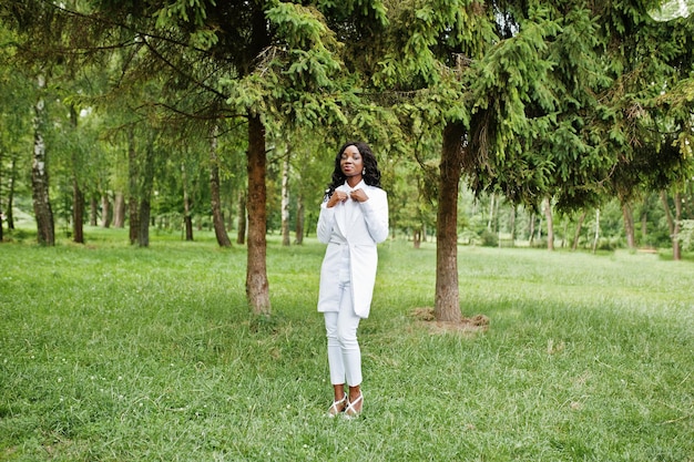 Porträt eines stilvollen schwarzen afroamerikanischen Mädchens, das im grünen Park bleibt
