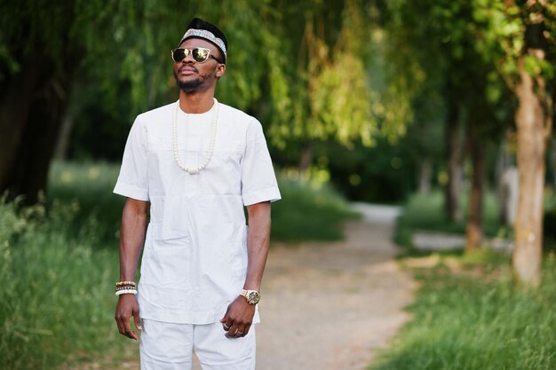 Porträt eines stilvollen und reichen schwarzen Afroamerikaners auf weißer Kleidung, Sonnenbrille und Hut