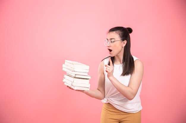 Porträt eines Studentenmädchens mit Brille, die mit Büchern in ihren Händen aufwirft. Bildungskonzept und Hobbys.