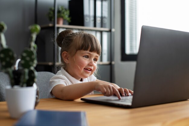 Porträt eines süßen Mädchens, das im Büro am Laptop arbeitet